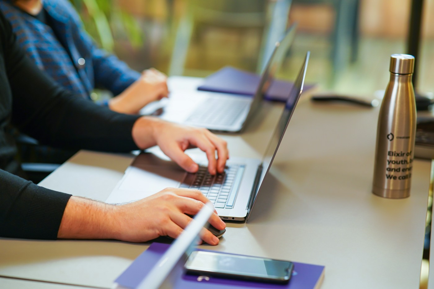 Colleagues using laptops around a shared meeting table